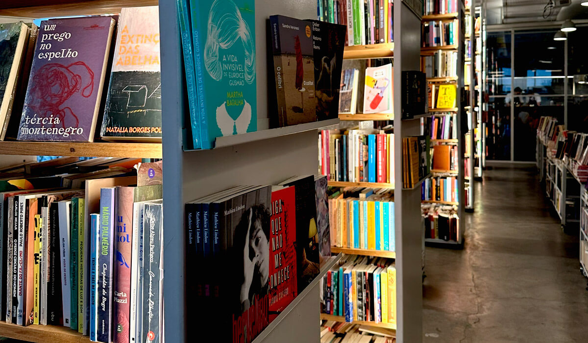 Corredor de livraria com estantes cheias de livros de autores brasileiros