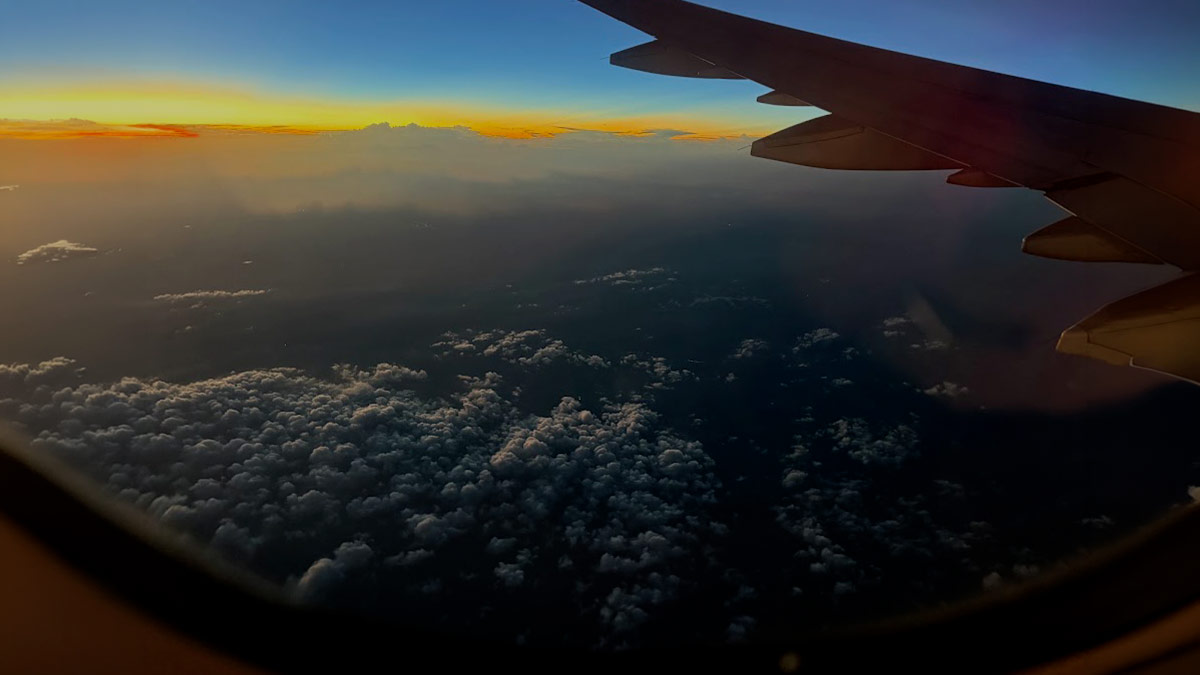 Vista da janela de um avião ao amanhecer sobre as nuvens